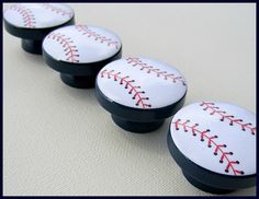 four baseball knobs with red stitching on them sitting next to eachother