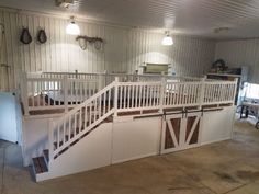 the inside of a horse barn with white railings