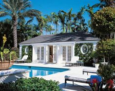 a house with a pool and palm trees in the back ground, surrounded by greenery