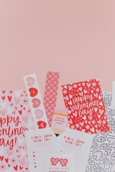 valentine's day cards and envelopes laid out on a pink background