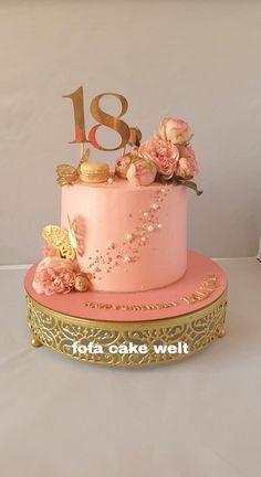 a pink and gold cake with flowers on top