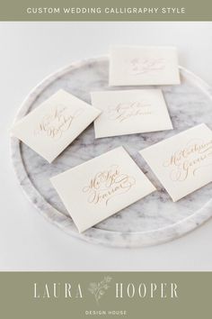 four place cards on a marble platter with gold calligraphy in the middle and below