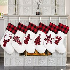 christmas stockings hanging from the fireplace in front of a mantel decorated with red and white plaid