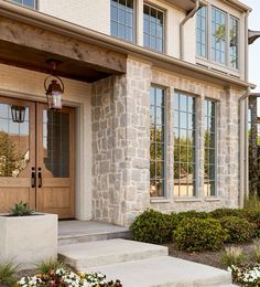 a house with stone steps leading up to the front door and entry way, surrounded by flowers