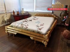 a bed made out of bamboo sticks in a room with wooden flooring and windows