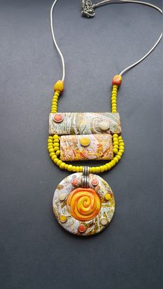 two necklaces with yellow beads on a black surface, one has an orange pendant and the other is a green bead