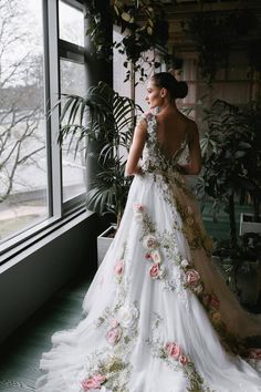 a woman in a wedding dress looking out the window