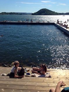 people are sitting on the dock by the water