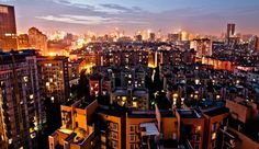 the city skyline is lit up at night, with tall buildings in the foreground