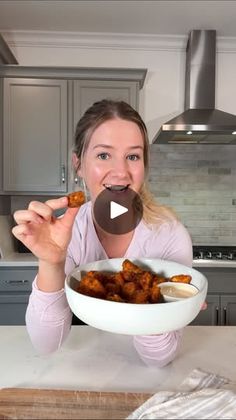 a woman sitting at a kitchen table with a bowl of food in front of her