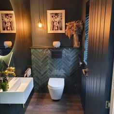 a bathroom with two pictures on the wall and a toilet next to it in front of a mirror