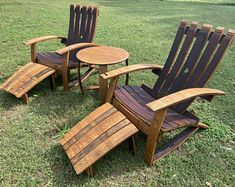 three wooden lawn chairs sitting on top of a grass covered field next to a small table