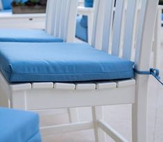 three white chairs with blue cushions on them