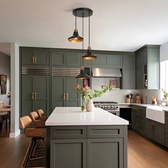 a large kitchen with green cabinets and white counter tops, along with wooden flooring