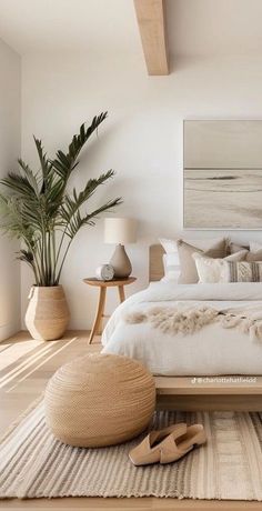 a bedroom with white walls and wooden flooring is furnished with natural materials such as rugs, pillows, and bed linens