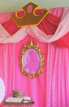 a princess themed bedroom with pink curtains and a gold crown on the headboard,