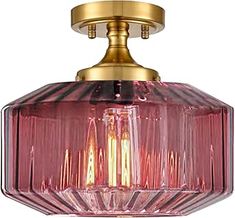 a pink glass light fixture hanging from a gold ceiling fixture with two lights on each side