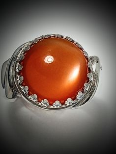 ORANGE MOONSTONE, Ring, Very Rare Quality! 11.5mm, AAA. Gem, Sterling Silver, Size 61/2, RC3.orang.ms.Please tell me your size. RING BOX#4 This is the only orange moonstone I have in my collection. The stone is rare and beautiful.  VERY RARE QUALITY GREAT CHATOYANCY! GREAT POLISH! GREAT CUT GREAT COLOR All of my stones are hammer set. We design jewelry to last a lifetime. This ring is excellent and strong. It should last forever.  Thank you for considering my work. LuvBruce Location: Celtic Jewelry Gift Moonstone Ring With Polished Finish, White Gold Round Cabochon Gemstones, Elegant Round Orange Gemstones, Formal Polished Round Moonstone Ring, Formal Polished Moonstone Ring, Round White Gold Polished Cabochons, Polished White Gold Cabochons, Elegant Amber Crystal Ring, Anniversary Cabochon Gemstones