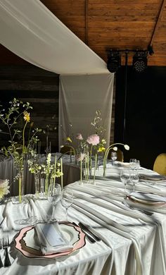 the table is set with white linens and flowers in glass vases on it