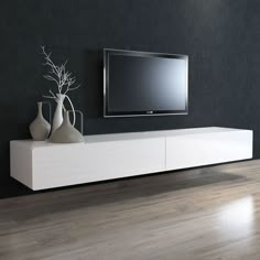 a flat screen tv sitting on top of a wooden entertainment center next to vases