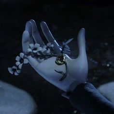 a hand with a ring on it is holding something in the air that looks like flowers