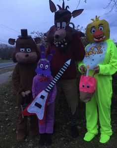 three people in animal costumes standing next to each other on the side of a road