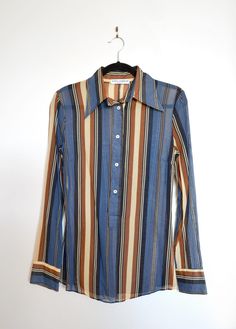 Make a bold statement with this striped button-up shirt from Dolce & Gabbana. This long-sleeve shirt is a perfect mix of retro charm and modern sophistication, featuring a striking blend of blue, brown, and beige tones. Half-placket front closure and zipper at side. Semi-sheer. Brand: Dolce & Gabbana Composition: 100% Cotton Size: IT 42 Shirt Stripes, Beige Tones, Brown And Beige, Semi Transparent, Vintage Vibes, Striped Blouse, Dolce & Gabbana, Blue Brown, Womens Clothing Tops