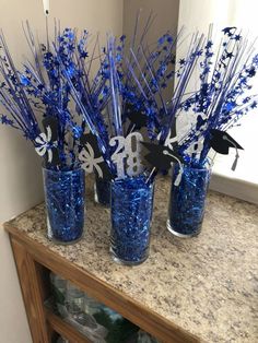 blue glass vases with silver and black paper cutouts in them on a counter