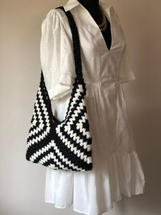 a black and white handbag hanging on a wall next to a mannequin