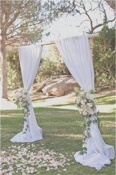 an outdoor wedding ceremony with white flowers and drapes