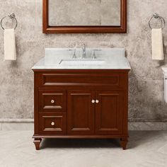 a bathroom vanity with a mirror above it and two towels hanging on the wall behind it