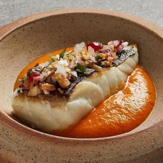 an orange and fish dish in a bowl on a counter top with other food items