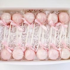 pink lollipops wrapped in white paper and tied with pink ribbon are displayed in a box