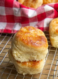 two biscuits stacked on top of each other on a wire rack next to a red and white checkered napkin