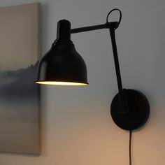 a black wall mounted light next to a painting