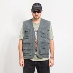 "Vintage 90's utility vest in gray - with a front zip - 4 main and few smaller pockets - materials: 35% cotton, 65% polyester SIZE size from the tag: L MEASUREMENTS chest: 49 inches (124 cm) length: 28 inches (71 cm) The model is 6'1\" (186 cm), measures 41-35-39 (104-88-100 cm) and typically wears clothing in size L CONDITION - 8/10 - The vest in good vintage condition. Minor signs of use. Washed, ready to wear." Cargo Vest Outfit Men, Utility Vest Outfit Men, Sleeveless Jacket Men, Utility Vest Outfit, Green Cargo Vest, Vest Outfits Men, Y2k Trousers, Cargo Vest, Utility Vest