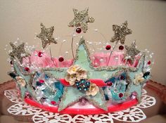 a tiara with flowers and stars on it is sitting on a doily in front of a wall