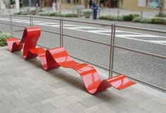 two red benches sitting on the side of a road