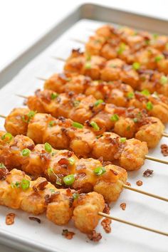 several skewers of food sitting on top of a white tray with green onions