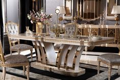 an elegant dining table with chairs and vases on the top, surrounded by gold accents