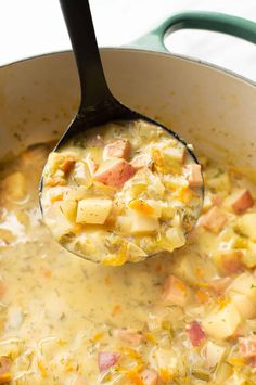 a ladle full of soup with potatoes and ham in it is being held by a spoon