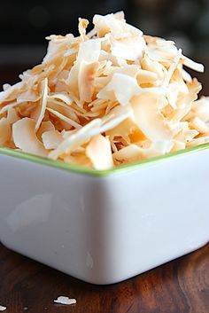 a white bowl filled with shredded food on top of a wooden table