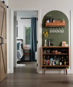 an open door leading into a room with wine glasses and liquor bottles on the shelves