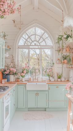 a kitchen filled with lots of pink flowers and greenery next to a large window