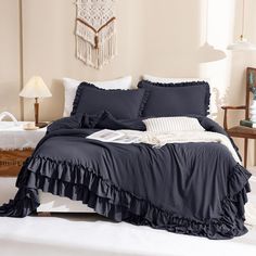 a bed with blue sheets and ruffles in a white room next to a window