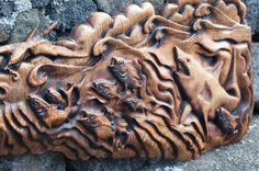 a carved wooden plaque with animals on it's face and some rocks in the background