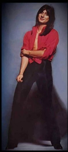 a man in red shirt and black pants posing with his arms folded over his chest