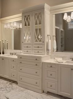 a large bathroom with marble floors and white cabinets in the center, along with two sinks