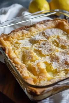 a baked dish with lemons and powdered sugar in the background on a wooden table