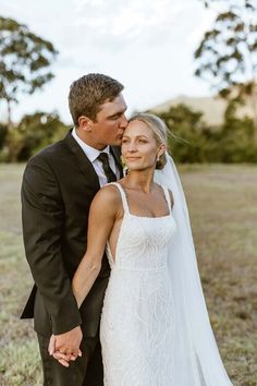 a bride and groom kissing in the field